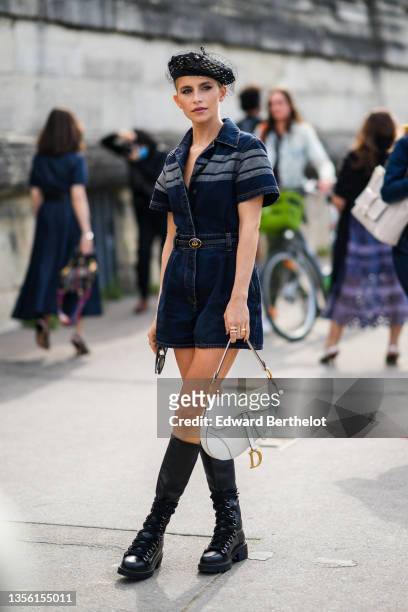 Caroline Daur wears a black mesh beret with lace from Dior, a navy blue denim short sleeves short jumpsuit with three gray denim strap on the...