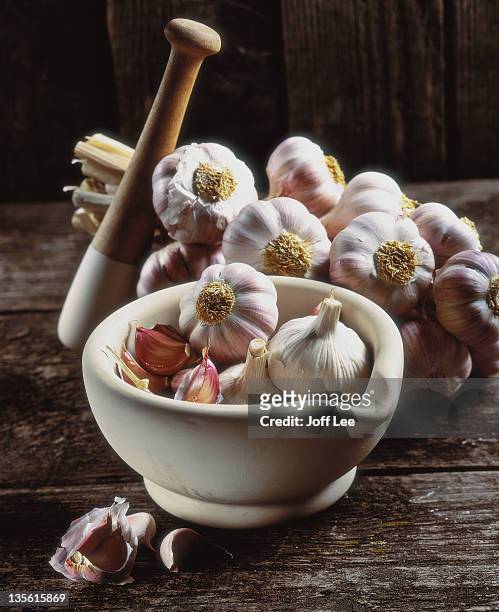 cloves & bulbs of garlic in pestle with mortar - garlic clove stock pictures, royalty-free photos & images