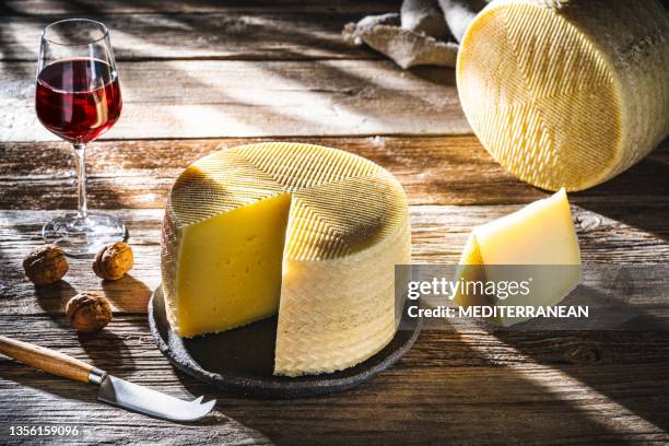 queso manchego rueda de queso 2 piezas y copa de vino tinto sobre rústico - queso manchego fotografías e imágenes de stock