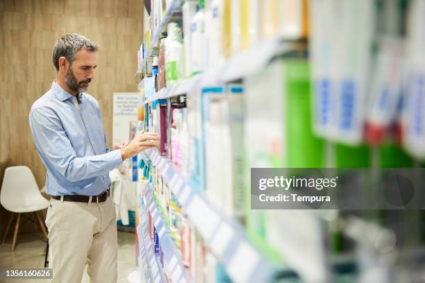 ein drogeriekunde wählt ein produkt in einer apotheke. - produktrückruf stock-fotos und bilder