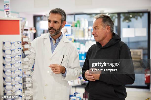 a client and an optician are choosing a new pair of glasses. - prescription glasses stock pictures, royalty-free photos & images