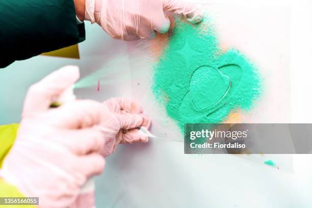 rubber-gloved hands with a can of automotive green paint spray the design through a saturn-shaped stencil - stencil foto e immagini stock