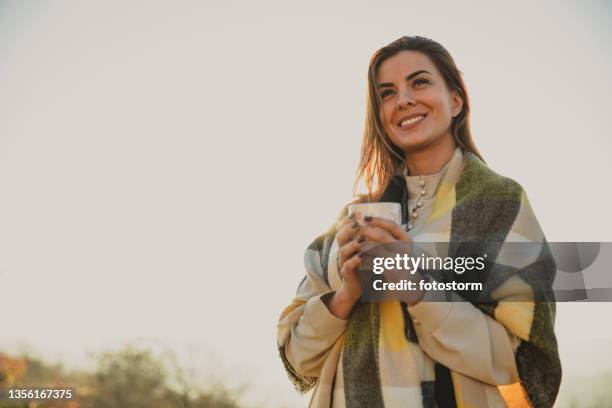 enjoying a beautiful day outside, keeping warm with a cozy scarf and a cup of tea - plaid scarf stock pictures, royalty-free photos & images