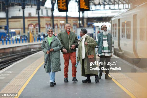 elderly friends walking together at station - quai de gare photos et images de collection