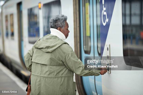 senior woman opening door of train - khaki green stock pictures, royalty-free photos & images