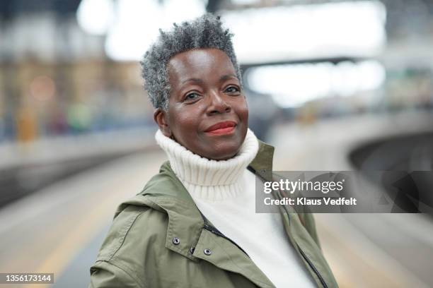 senior woman wearing turtleneck at station - self satisfaction foto e immagini stock