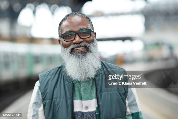 senior man with eyeglasses standing at railroad station - hipster senior man stock pictures, royalty-free photos & images