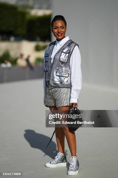 Guest wears diamond earrings, a white puffy sleeves shirt, a silver mesh with shiny leather pockets sleeveless jacket, a gold Juste Un Clou bracelet...