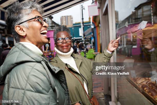 senior woman doing window shopping with friend - friends donut stock pictures, royalty-free photos & images