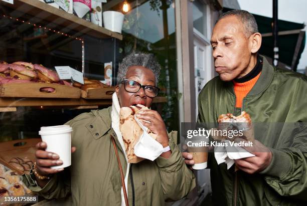 senior friends eating food in bakery shop - donut man bildbanksfoton och bilder