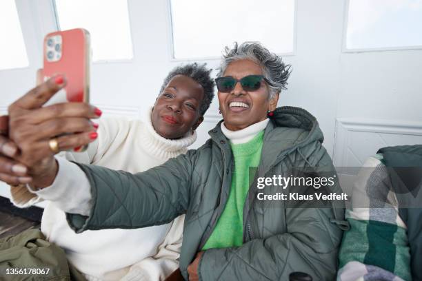 happy female friends taking selfie with smart phone - young at heart stock pictures, royalty-free photos & images