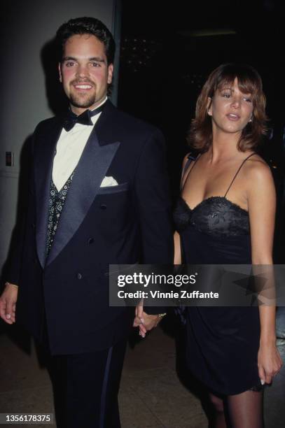 American baseball player Mike Piazza, wearing a black tuxedo and a bow tie, holding hands with an unspecified woman, who wears a black strapless...