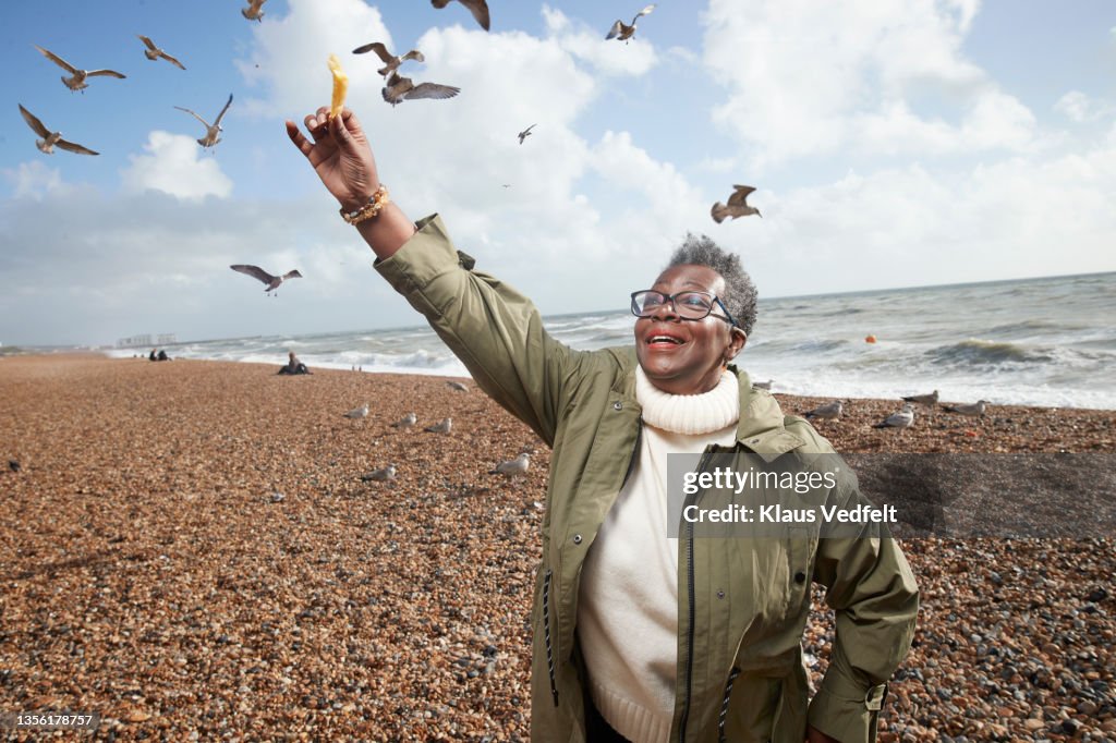 Senior woman feeding french fries to bird