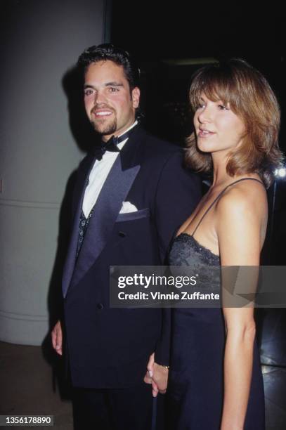 American baseball player Mike Piazza, wearing a black tuxedo and a bow tie, holding hands with an unspecified woman, who wears a black strapless...