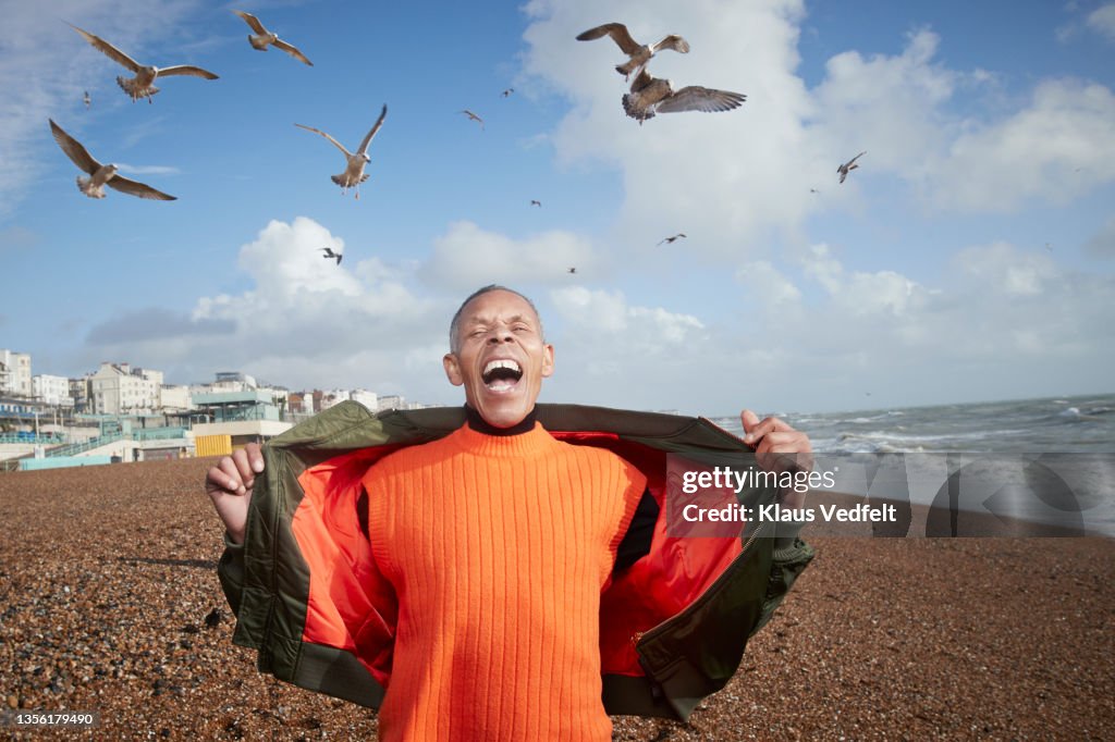 Senior man screaming while birds flying at beach