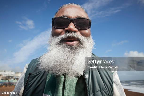 smiling senior man with white beard at beach - close up man pose foto e immagini stock