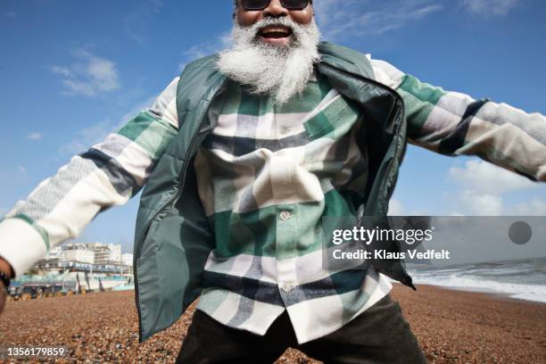 cheerful senior man with beard jumping at beach - chaqueta a cuadros fotografías e imágenes de stock