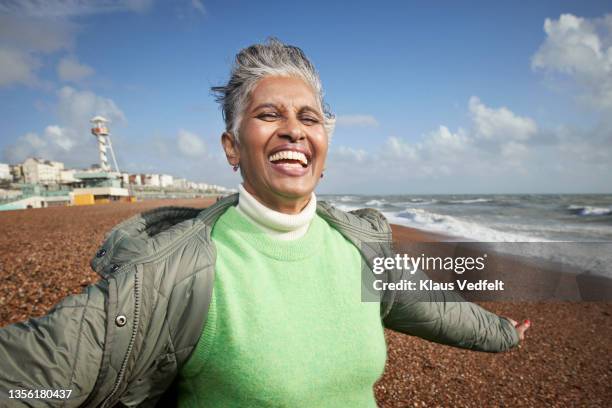 happy senior woman enjoying at beach - stralende lach stockfoto's en -beelden