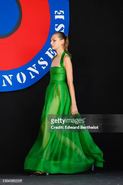 Model wears a green shiny satin silk tank-top / square neck / long flowing dress, black shiny leather block heels ballerinas, rings, earrings, and...