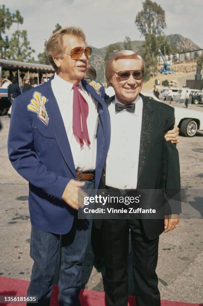 American singer, songwriter, and musician Buck Owens , wearing a blue blazer with a white shirt and jeans, with his arm around American singer,...