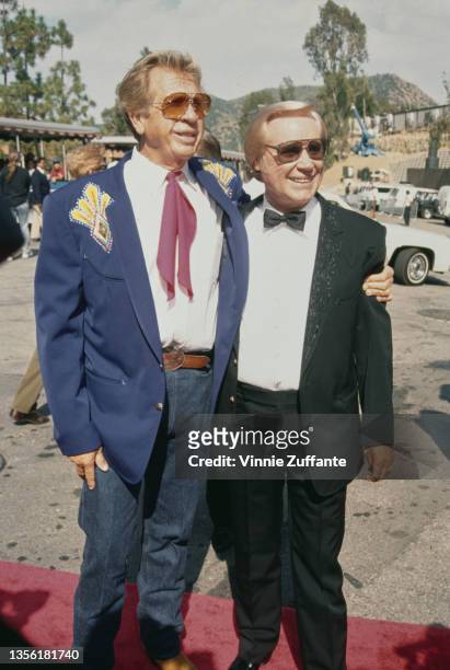 American singer, songwriter, and musician Buck Owens , wearing a blue blazer with a white shirt and jeans, with his arm around American singer,...