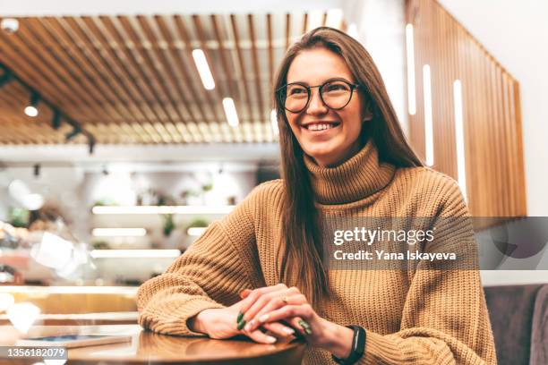 portrait of a beautiful young businesswoman is smart glasses is sitting at the cafe table - nerd sweater stock pictures, royalty-free photos & images