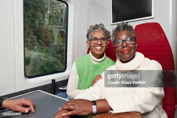 portrait of smiling elderly female friends in train - alte und junge lesbische frauen stock-fotos und bilder