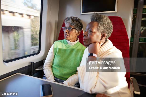 contemplative elderly women looking through window in train - young at heart bildbanksfoton och bilder