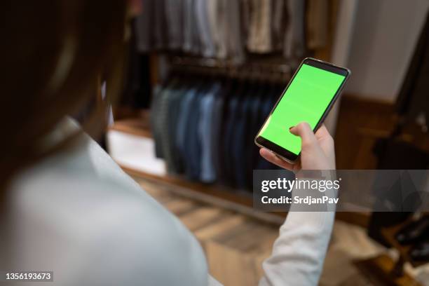 unrecognizable female owner of boutique using mobile phone with a green screen on - shopping centre screen stock pictures, royalty-free photos & images