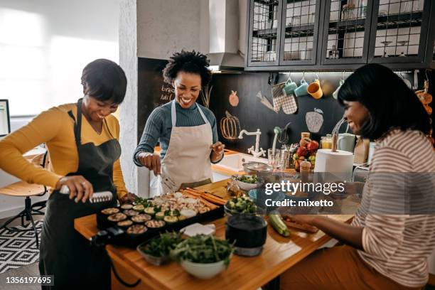 three female friends cooking food in kitchen - holiday preparation stock pictures, royalty-free photos & images