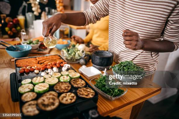 mujer vertiendo aceite de cocina en la parrilla de barbacoa mientras prepara la comida - vegan food fotografías e imágenes de stock