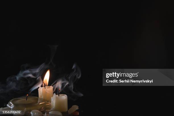 a few candles isolated over dark background. used, almost extinguished. burned out. copy space. mystical smoke swirls in the darkness. - smoking death stock pictures, royalty-free photos & images