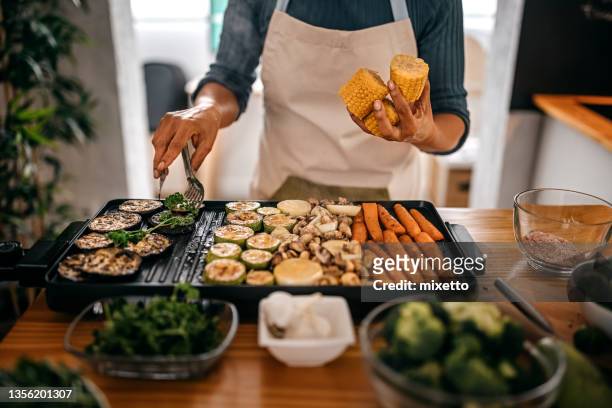 woman picking up grilled eggplant from barbecue - cooked mushrooms stock pictures, royalty-free photos & images