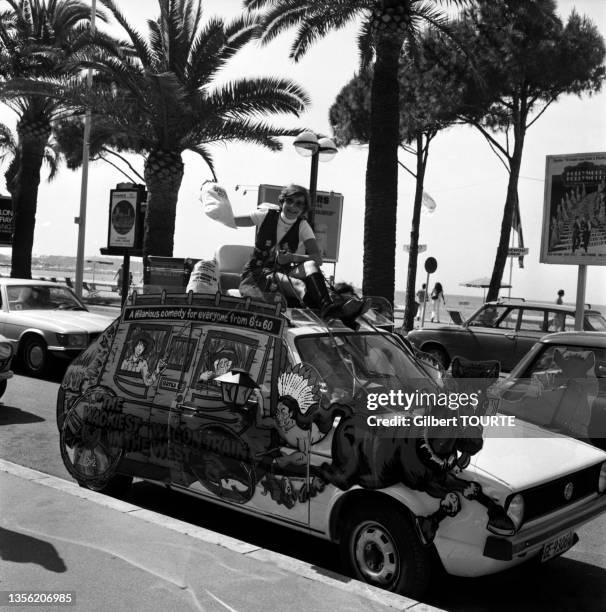 Une femme est assise sur le toit d'une voiture publicitaire pour le film 'The Wackiest Wagon Train in the West' lors du Festival de Cannes en mai 1976