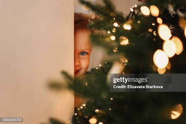 a little girl child in a dress is getting ready for christmas decorating a christmas tree in a cozy decorated room during the new year vacations  at home indoor. a kid waiting for a holiday - christmas anticipation stock pictures, royalty-free photos & images