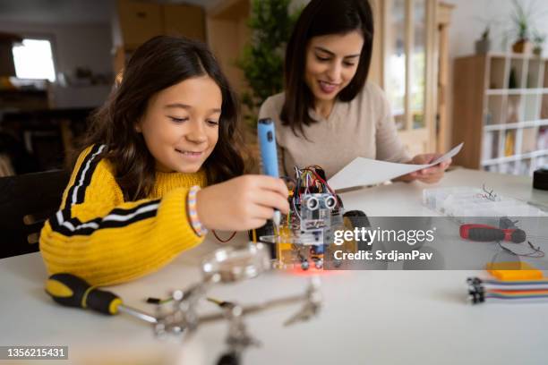 with a help of her proud mother, intelligent schoolgirl, making a prototype of an autonomous self-drive robotic car - school science project stock pictures, royalty-free photos & images