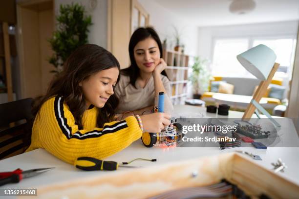 proud mother observing her daughter while she making a self-driven robotic car - home school stock pictures, royalty-free photos & images