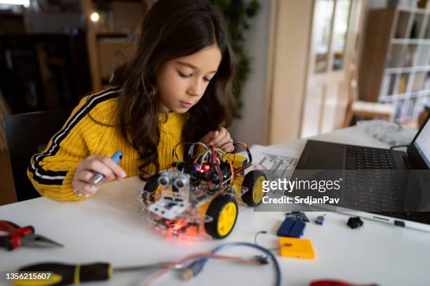 dedicated schoolgirl, observing the prototype of robotic car, she testing - child with robot stockfoto's en -beelden