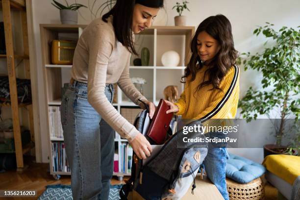 colegiala, empacando su mochila con útiles escolares con la ayuda de su madre - preparación fotografías e imágenes de stock