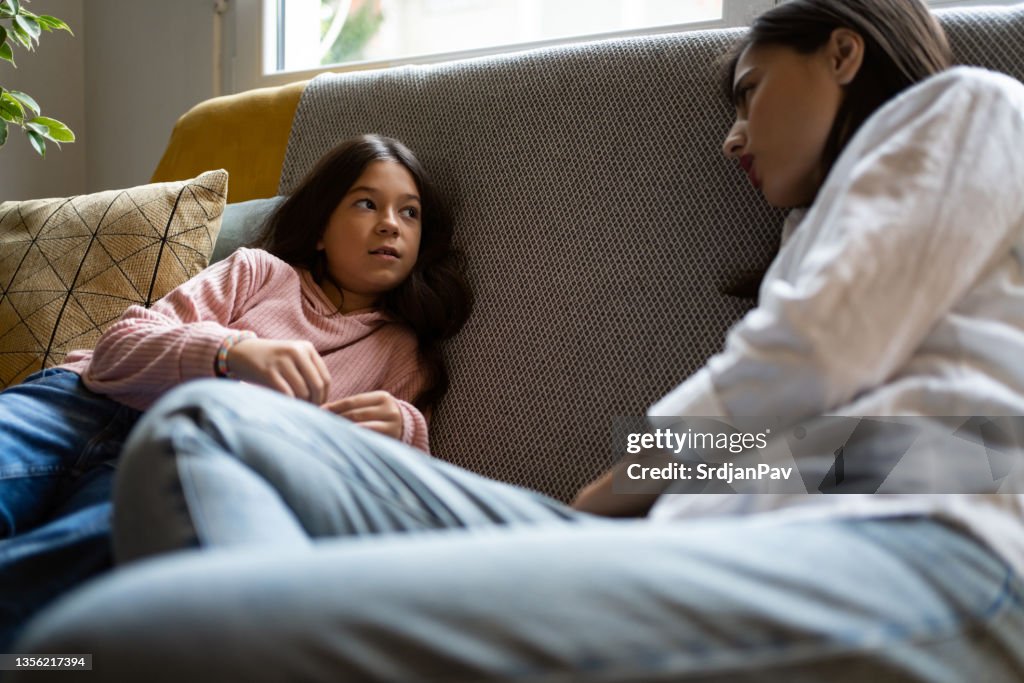 While sitting on sofa, mother and daughter having a casual conversation