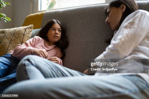 while sitting on sofa, mother and daughter having a casual conversation - serious child stock pictures, royalty-free photos & images