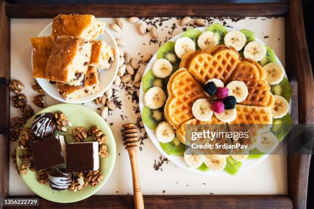 plate with waffles, fruits and chocolate cakes - honinglepel stockfoto's en -beelden