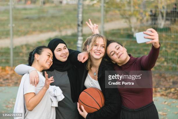 group of teenage girls taking selfies on basketball court - youth culture bildbanksfoton och bilder