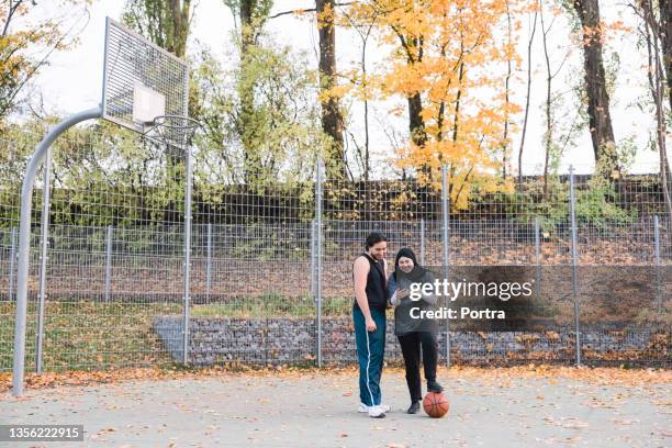 teenager-freunde mit handy auf basketballplatz - ethnische integration deutschland stock-fotos und bilder