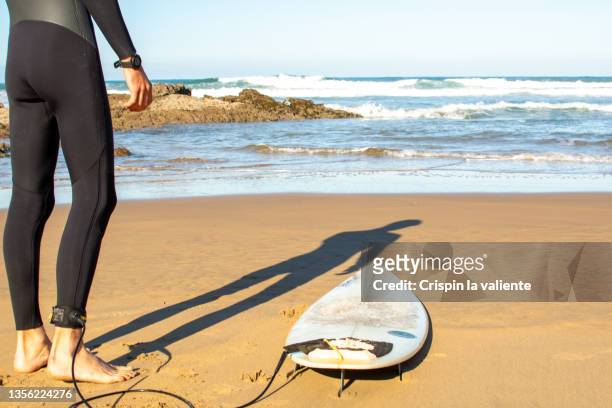 low section of foot surfer with surf leash to his board before entering the water. - neoprene fotografías e imágenes de stock