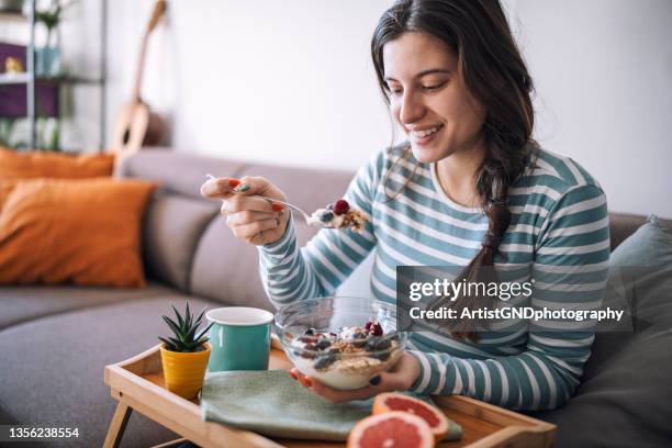 smiling woman having breakfast in the morning at home - bowl of blueberries stockfoto's en -beelden