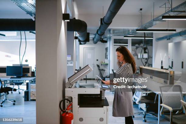 woman using the photocopier machine at the office - by the photocopier stockfoto's en -beelden