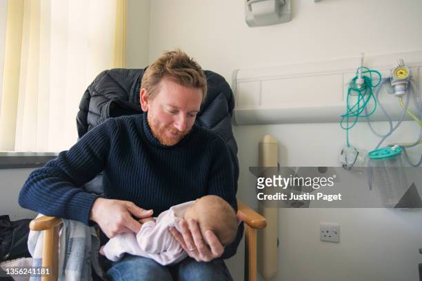 father looks lovingly at his newborn baby daughter - birthing chair stock pictures, royalty-free photos & images