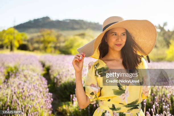 smiling young woman standing in a field of lavender wearing a sun hat - wide brim stock pictures, royalty-free photos & images