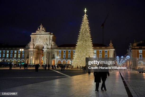 Locals and tourists walk near the city's main Christmas tree in Praça do Comercio, part of Christmas and New Year illuminations, during the COVID-19...